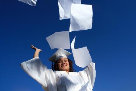 woman wearing graduation gown and celebrating